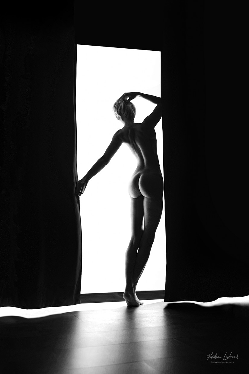Boudoir-Fotografie in schwarz-weiß. Aktfotografie am Fenster im Gegenlicht für ein spannendes Schattenspiel. Aktshooting